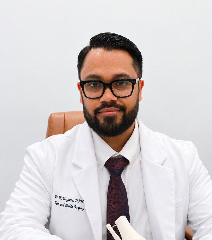 Dr. M. Nayeem, D.P.M., Medical Director at Happy Feet 4 All, holding an anatomical foot model