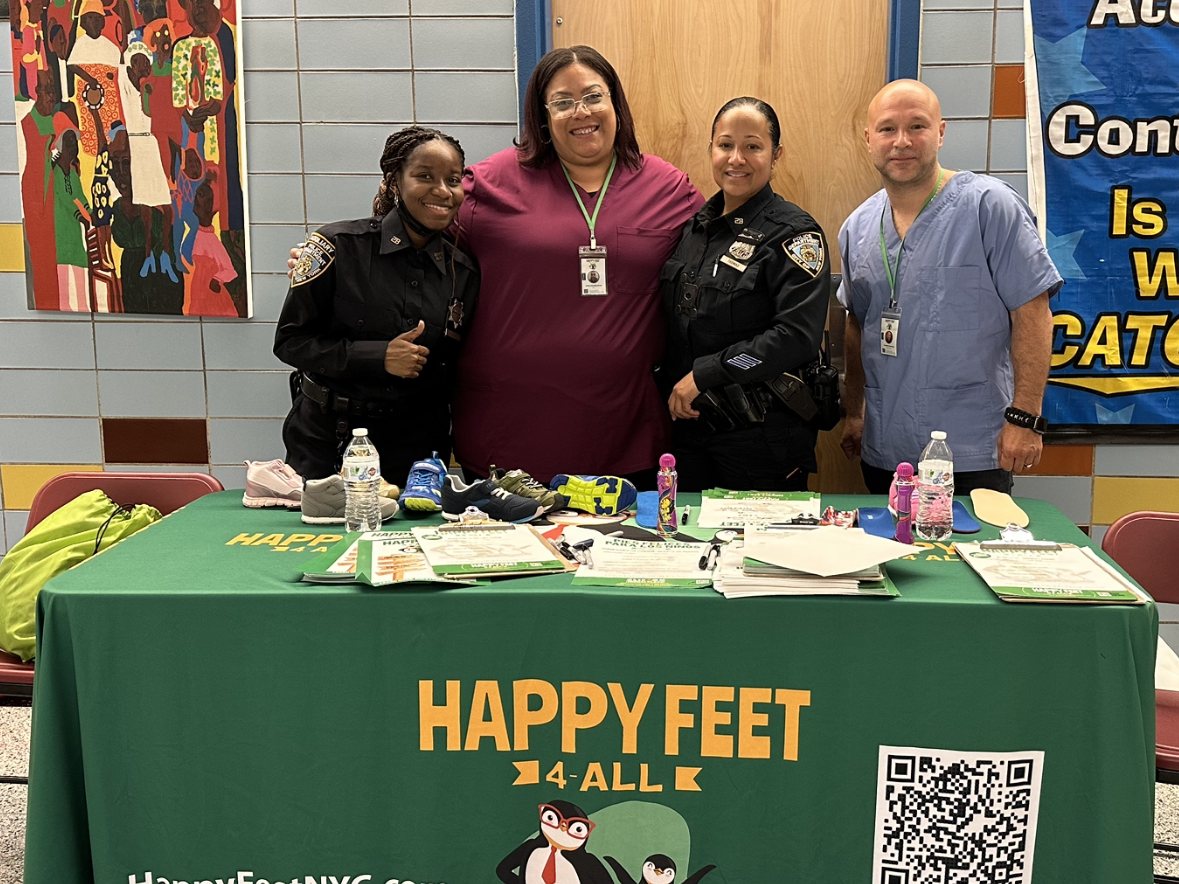 NYPD officers with the Happy Feet 4 All team at an on-site screening table in a school